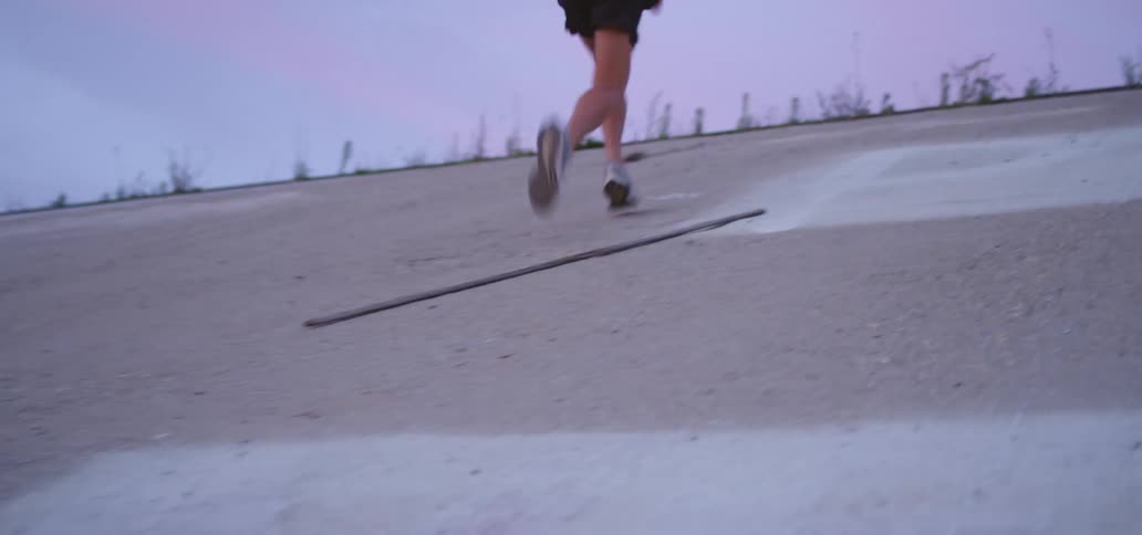 Young man running up a slope at sunset