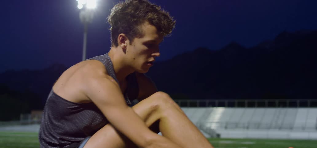 A teenager puts on his running shoes at a stadium