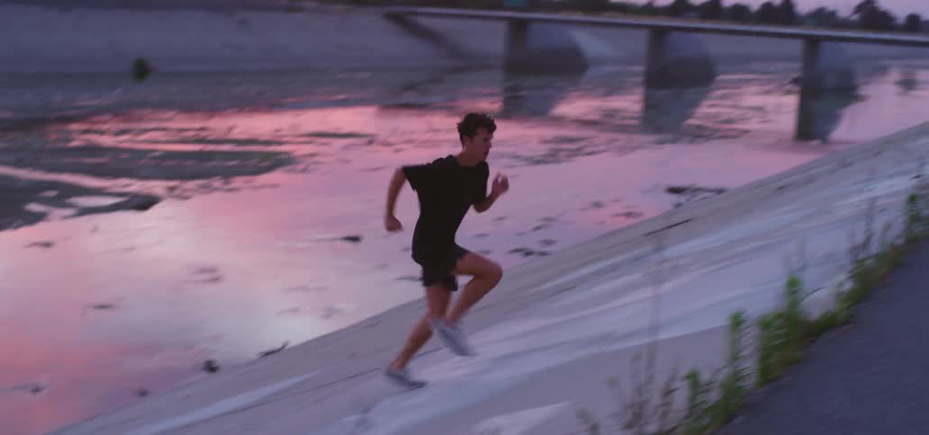 A male running up a steep incline near a river