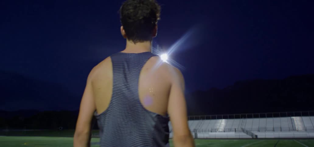 Young man walks on the field in a stadium at night