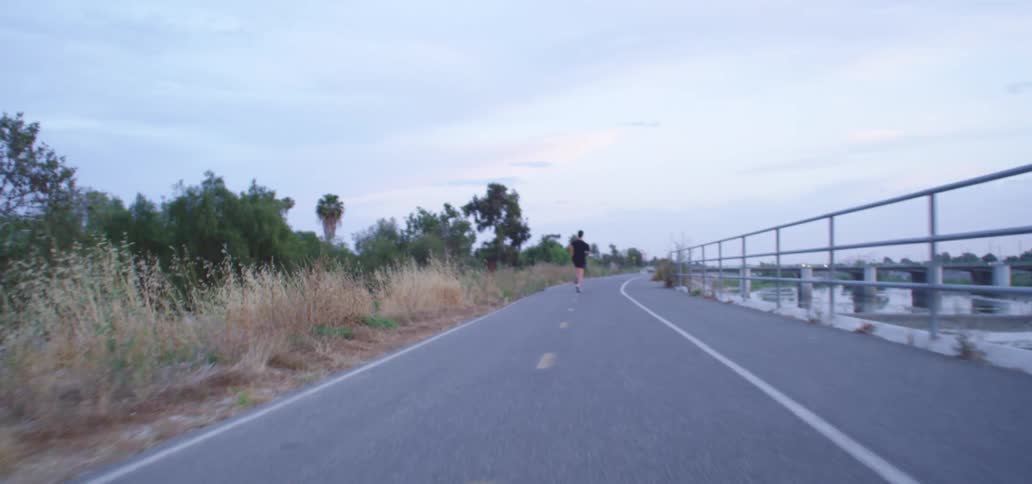 A male runs down a path next to a river