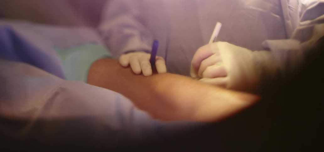 A surgeon writes on a patients leg in an operating room
