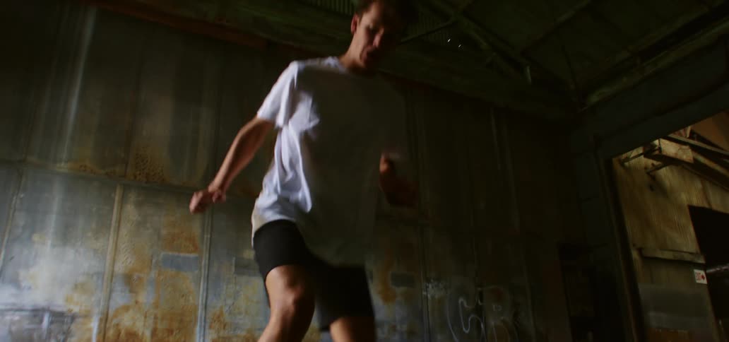 A man is exercising by jumping through a ladder on the ground