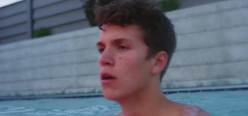 A young male in a swimming pool is training by continuously treading water