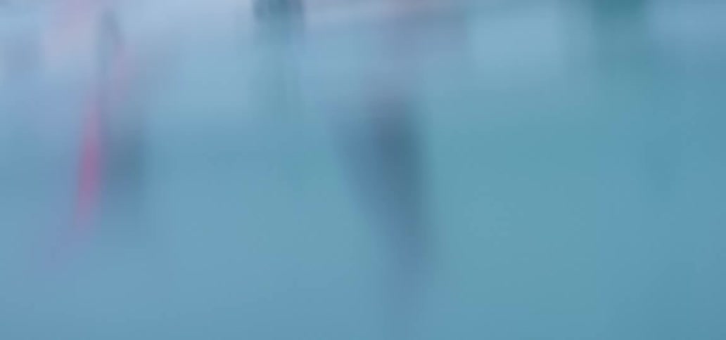 A man in a swimming pool exercising with trees a wall and the sky in the background