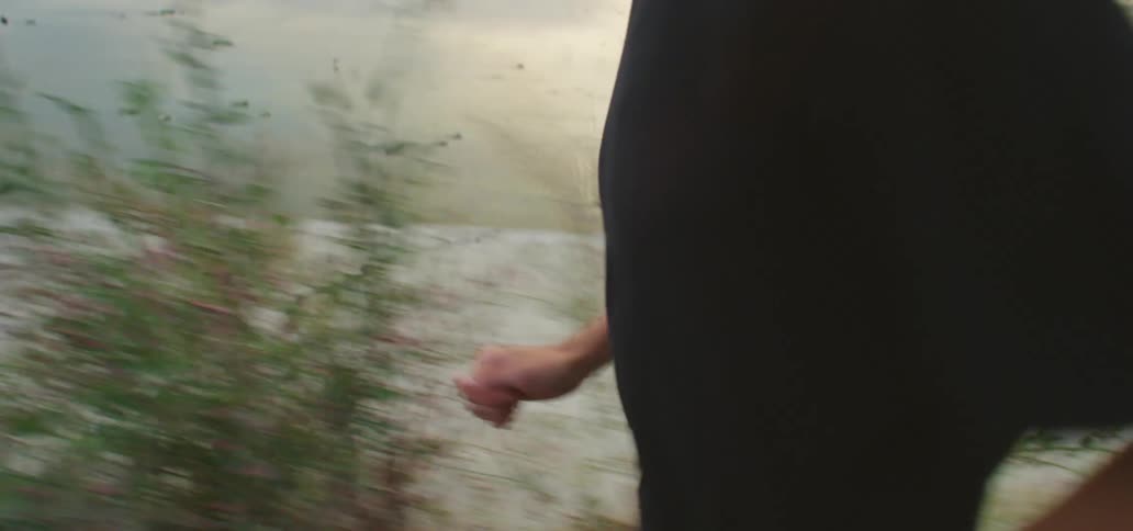 Man with a pair of white shoes black running shorts and a t shirt runs along an asphalt road on a cloudy day