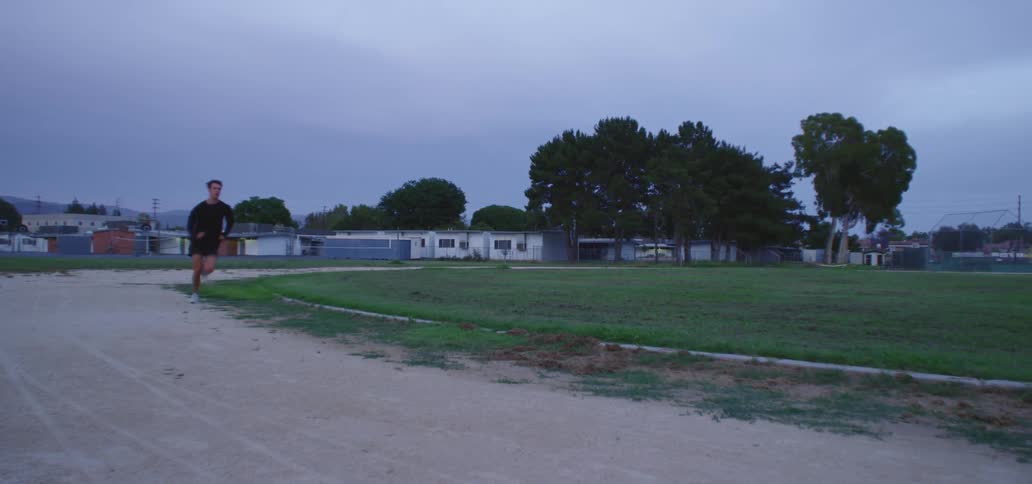 Athlete runs along dirt track near school buildings