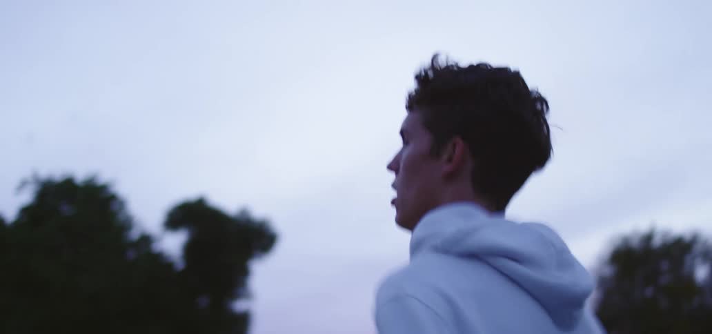 Man with a white hoodie runs and then slows down on a cloudy day