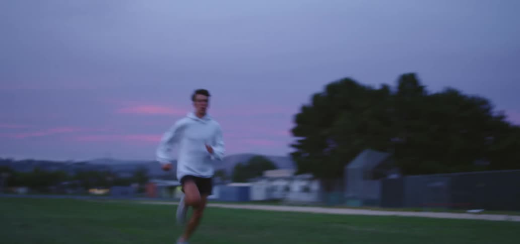 Young man exercises running on a park at sunset