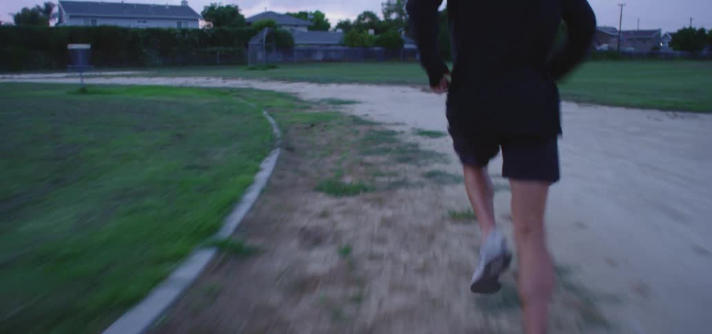 Young man exercises running in a track at sunset