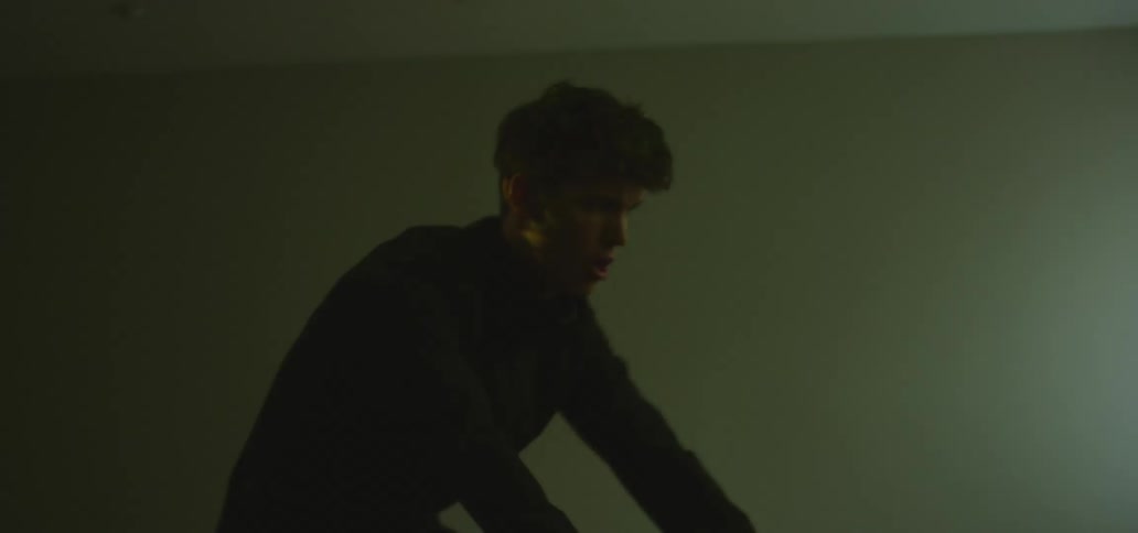 A male caucasian riding a stationary bike while sweating profusely