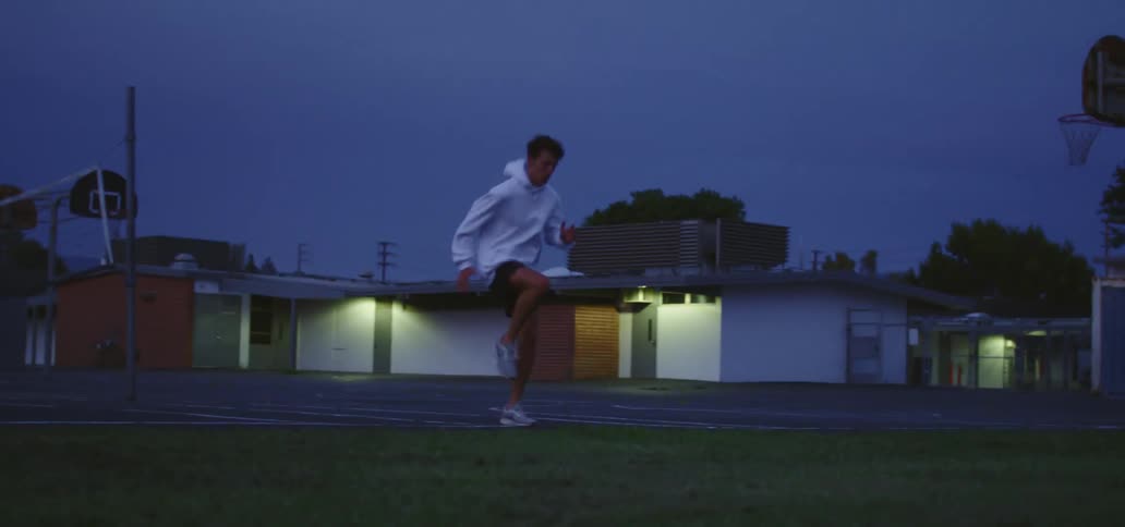Young man in a white hoodie and shorts does push ups and calisthenics in the early morning