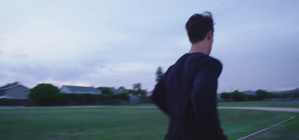 A teenager runs on a dirt track behind a neighborhood