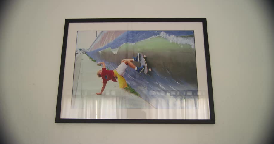 A painting of a boy on a skateboard hanging on a wall