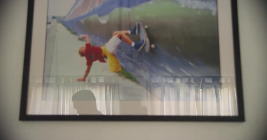 The shadow of a man walking past a painting hanging on a wall