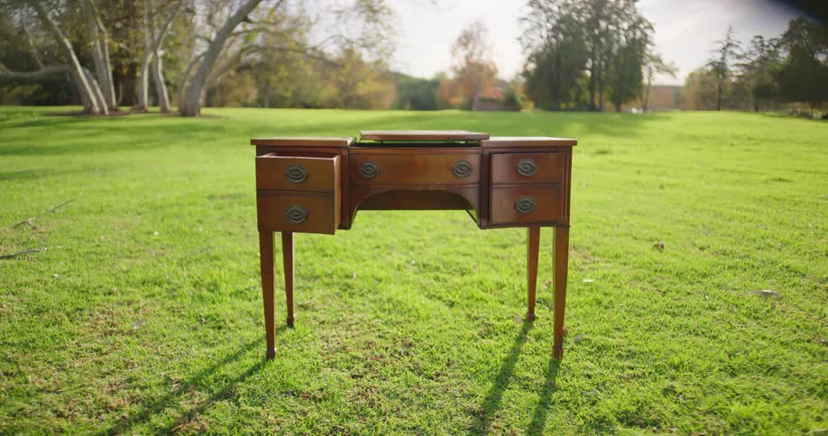 An antique desk sits outside in a park