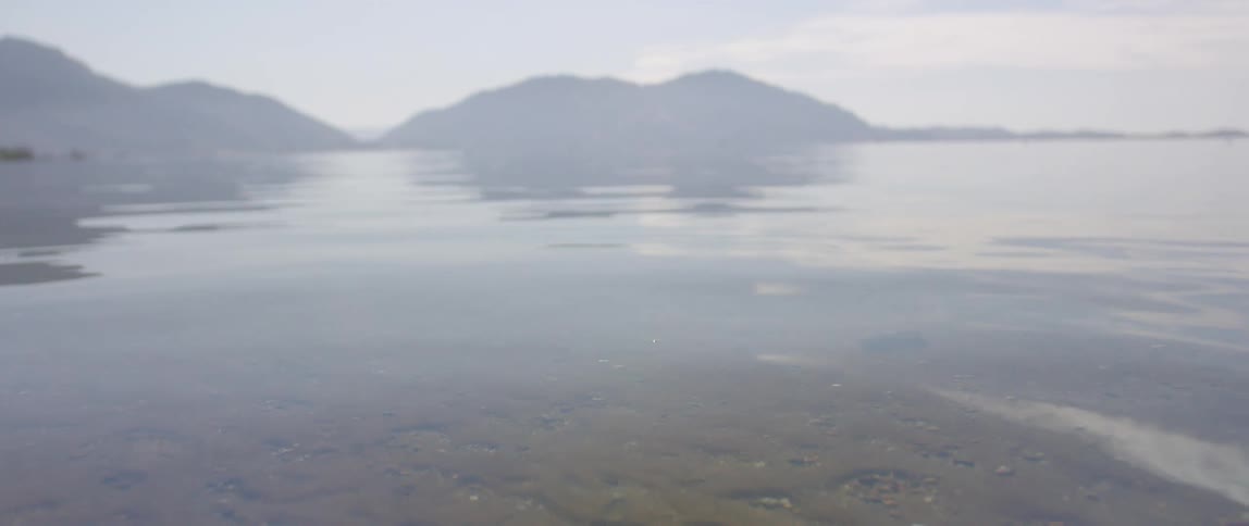Clear calm waters of a lake reflects the nearby mountains