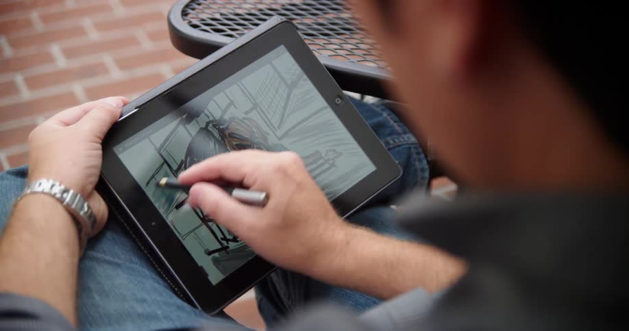 A man is drawing on his tablet outside