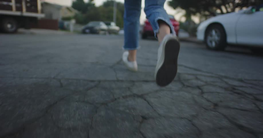 A woman running in the street with vehicles trees and the sky in the background
