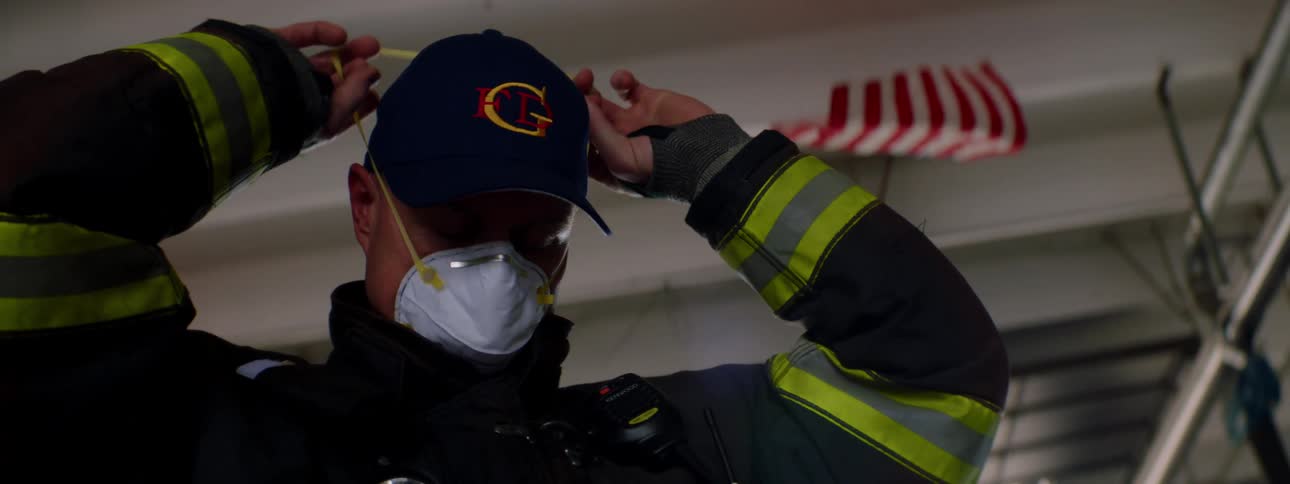 A firefighter is putting on a mask