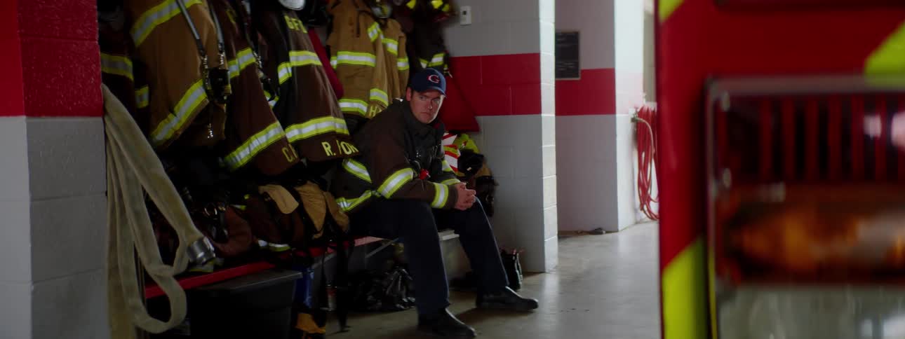 A firefighter sits on a bench near a fire truck