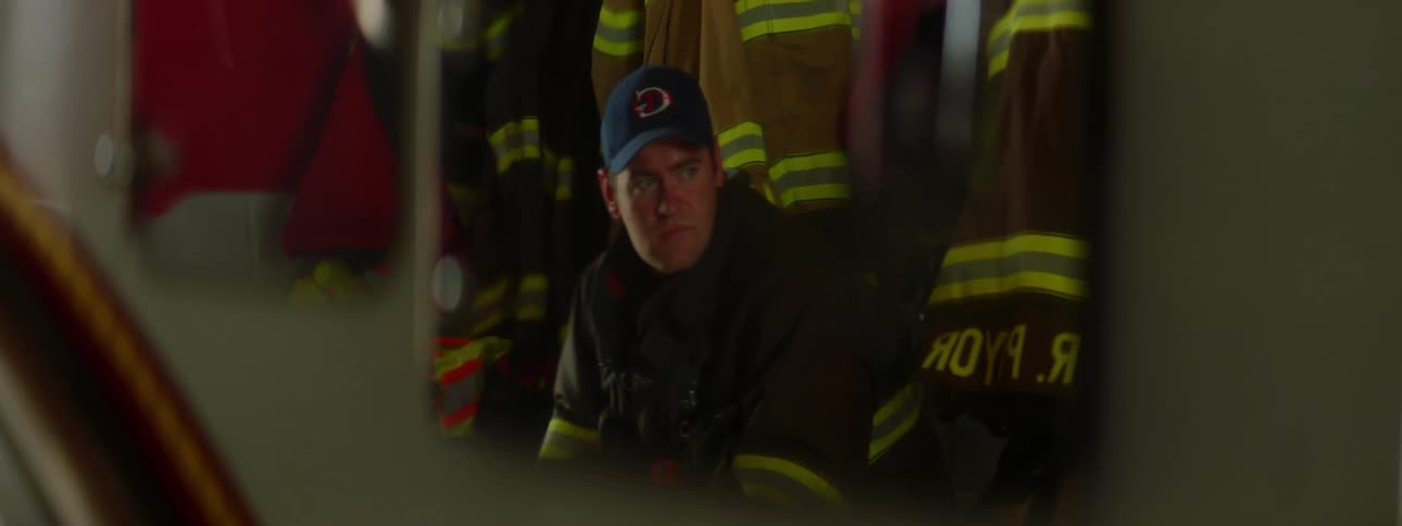 Mirror reflects firefighter sitting near firefighter coats