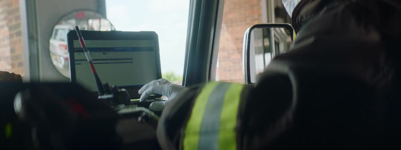 A firefighter sitting in a vehicle uses a computer