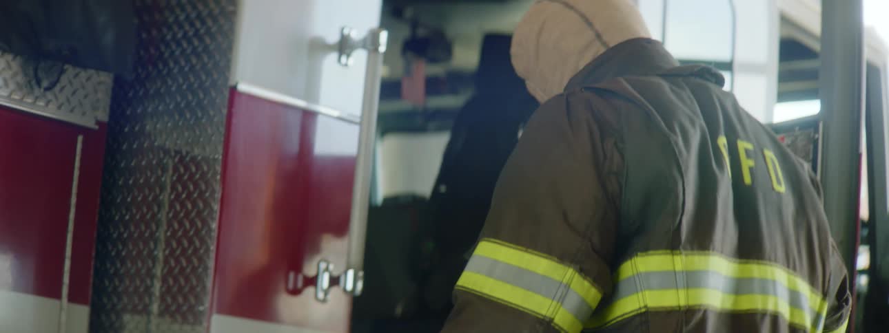 A firefighter puts on his jacket