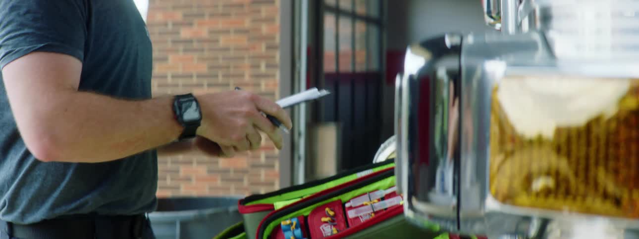 Man takes notes while checking equipment in front of a fire truck