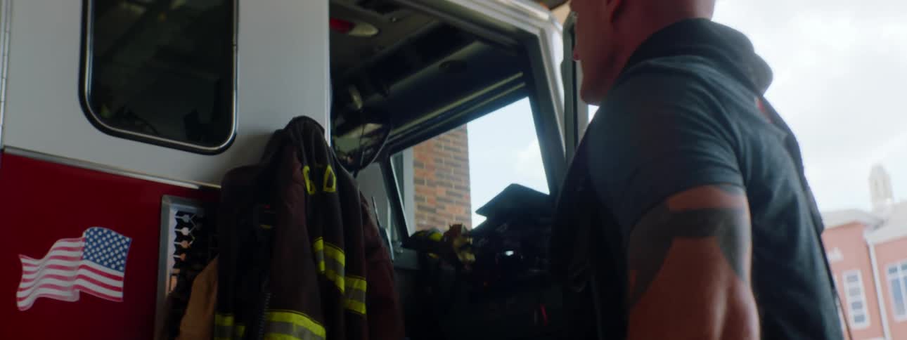 A firefighter is putting on their uniform outdoors