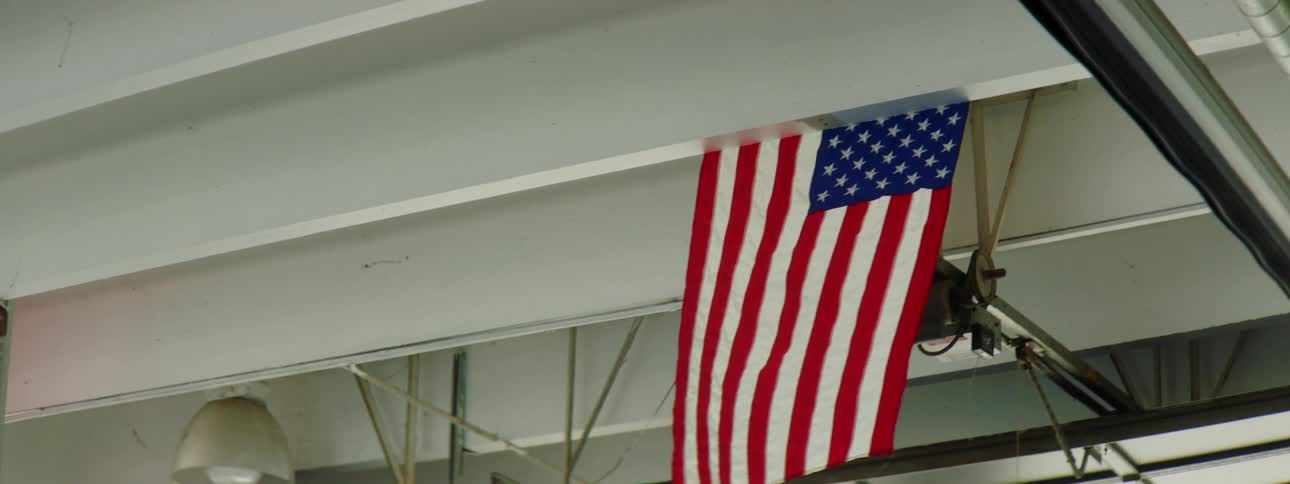 An american flag hangs from ceiling rafters in a building