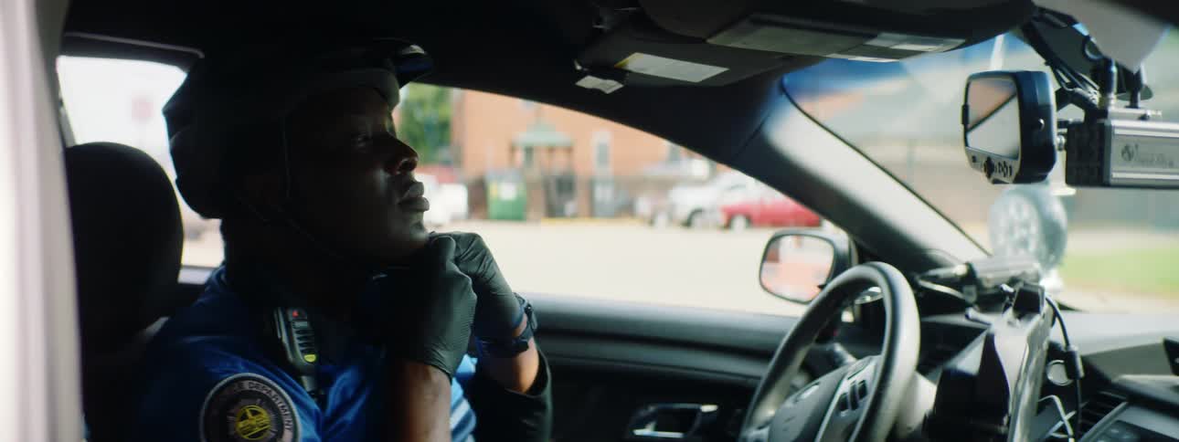 A police officer puts a helmet on and gets out of his car
