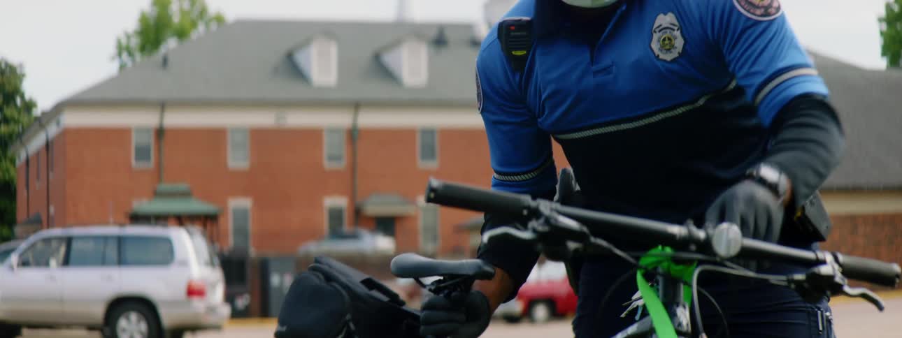 A police officer takes a bike off the back of his squad car and sets it on the ground