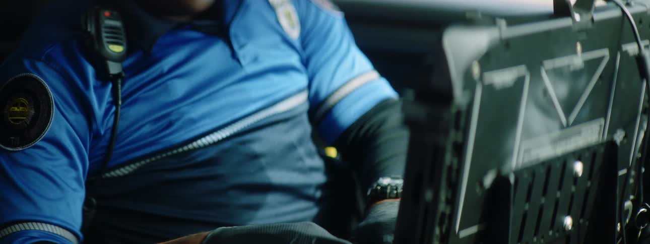 A police officer sitting in his car working on a computer