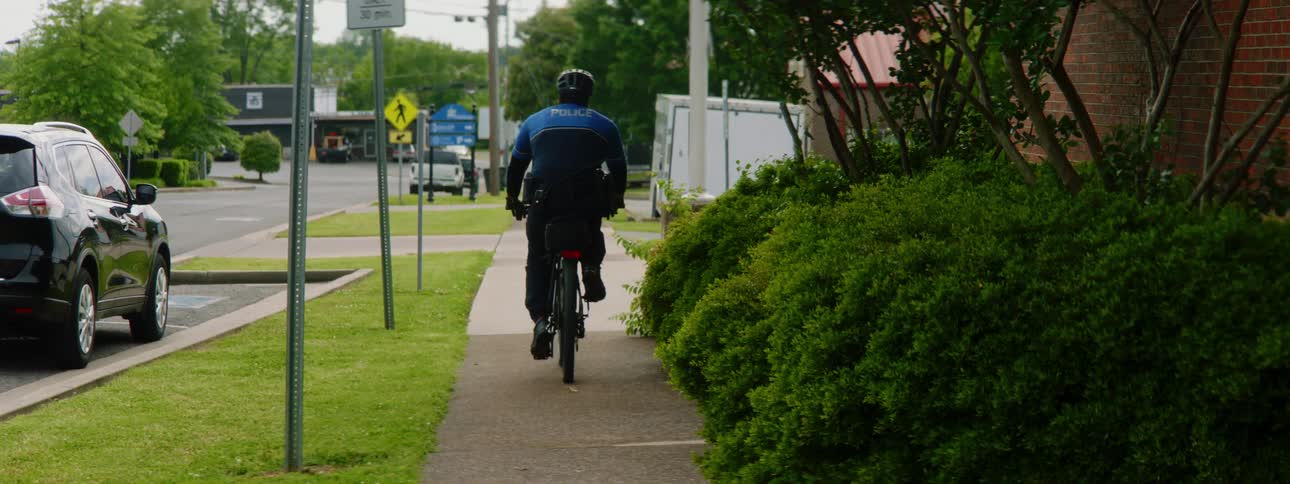 Police officer with a helmet and face mask rides a bicycle on a cycle road