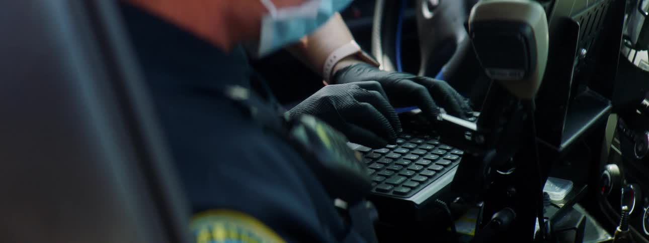 Police officers in a vehicle as one types on a computer