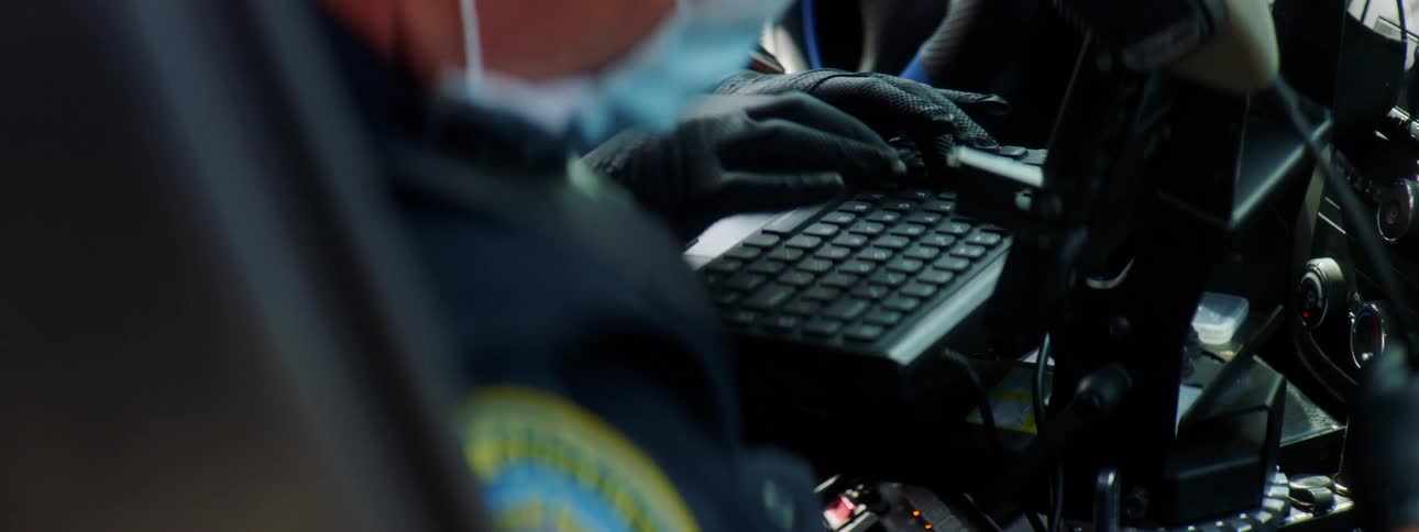 An officer is typing on a computer in his vehicle