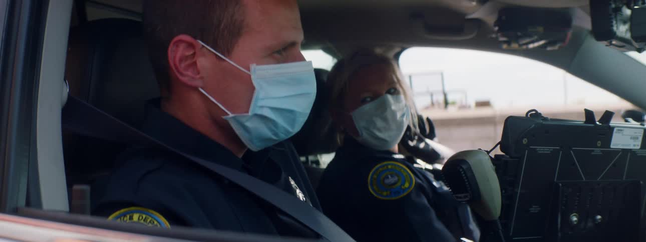 Two police officers put on their seatbelts while sitting in a police car