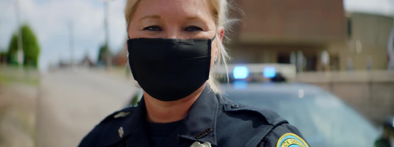 A female police officer stands outside of her police vehicle