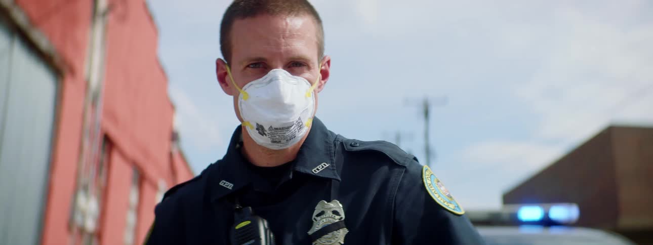 A police officer is standing outside on a cloudy day