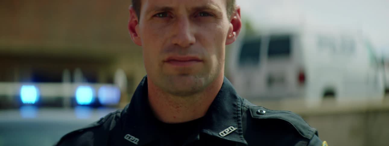 Close up of a police officer face standing in front of a patrol car outdoors