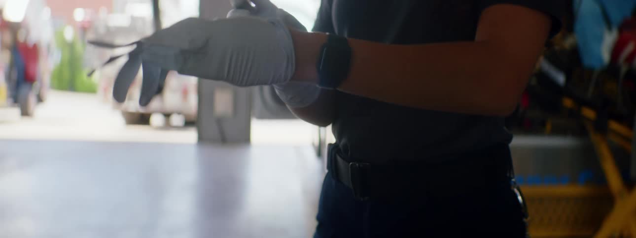 Female paramedic puts latex gloves on in front of an ambulance