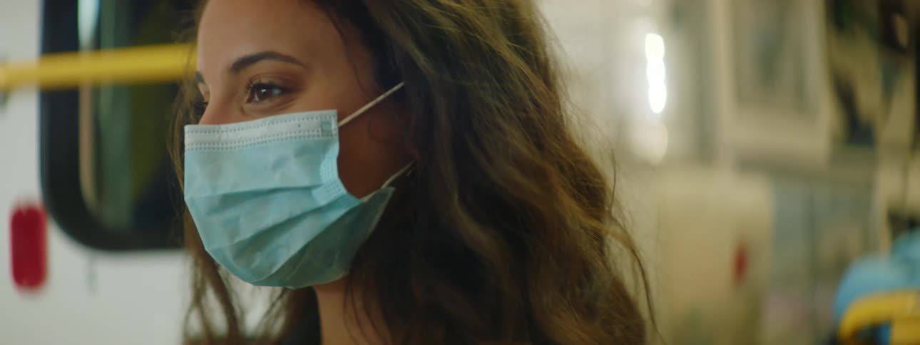 Young woman wearing face mask stands in front of an ambulance with the doors open