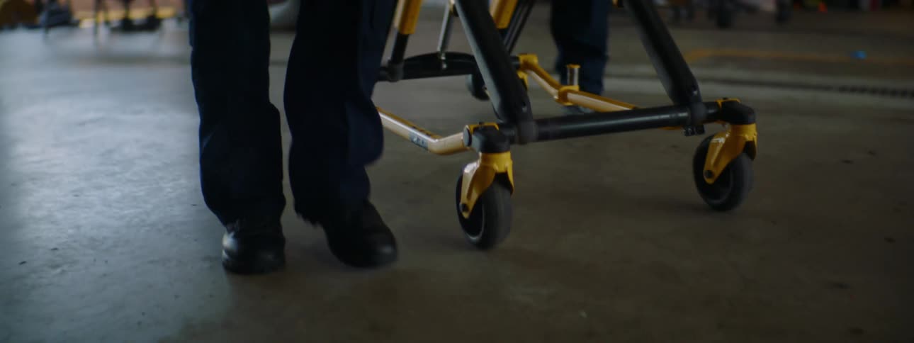 Two people are pushing a gurney towards the ambulance