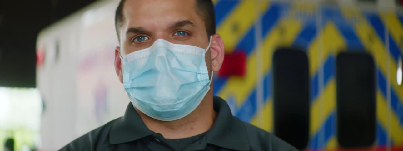 Paramedic with blue eyes wearing a face mask in front of an ambulance