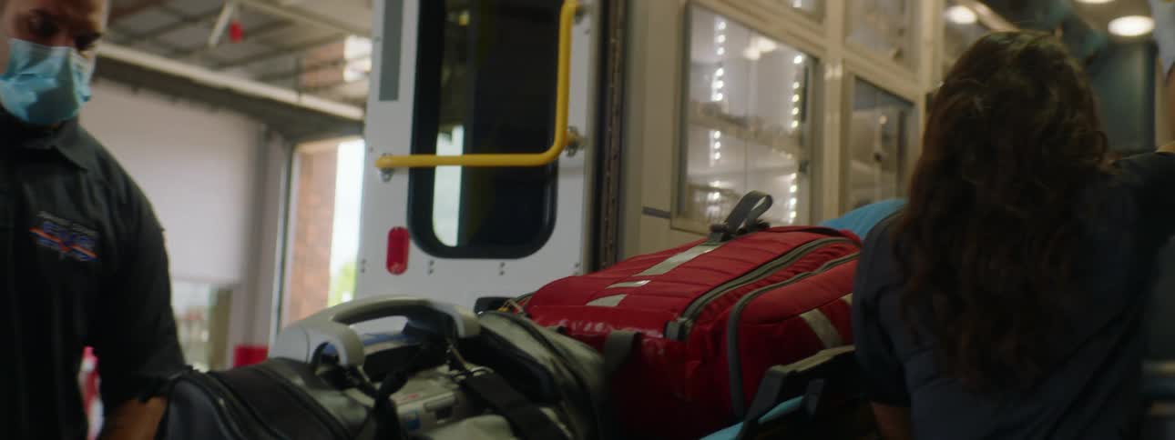 Two emergency medical technicians load stretcher into ambulance