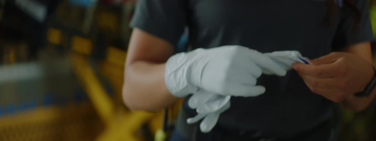 A female paramedic puts on gloves in front of a gurney