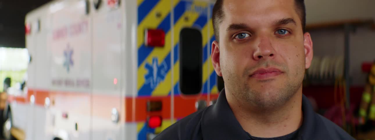 A firefighter poses in front of an ambulance parked at the fire station
