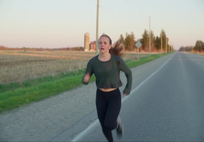 Female jogging along a road near a dry field in the country