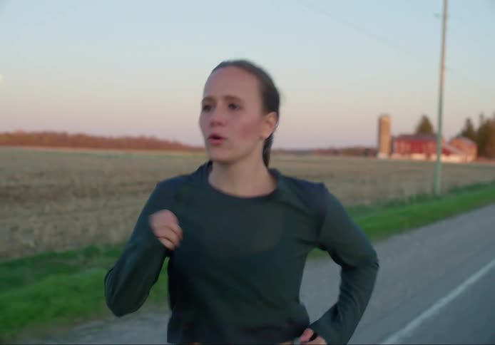 Close up of females face while jogging along a field in the country